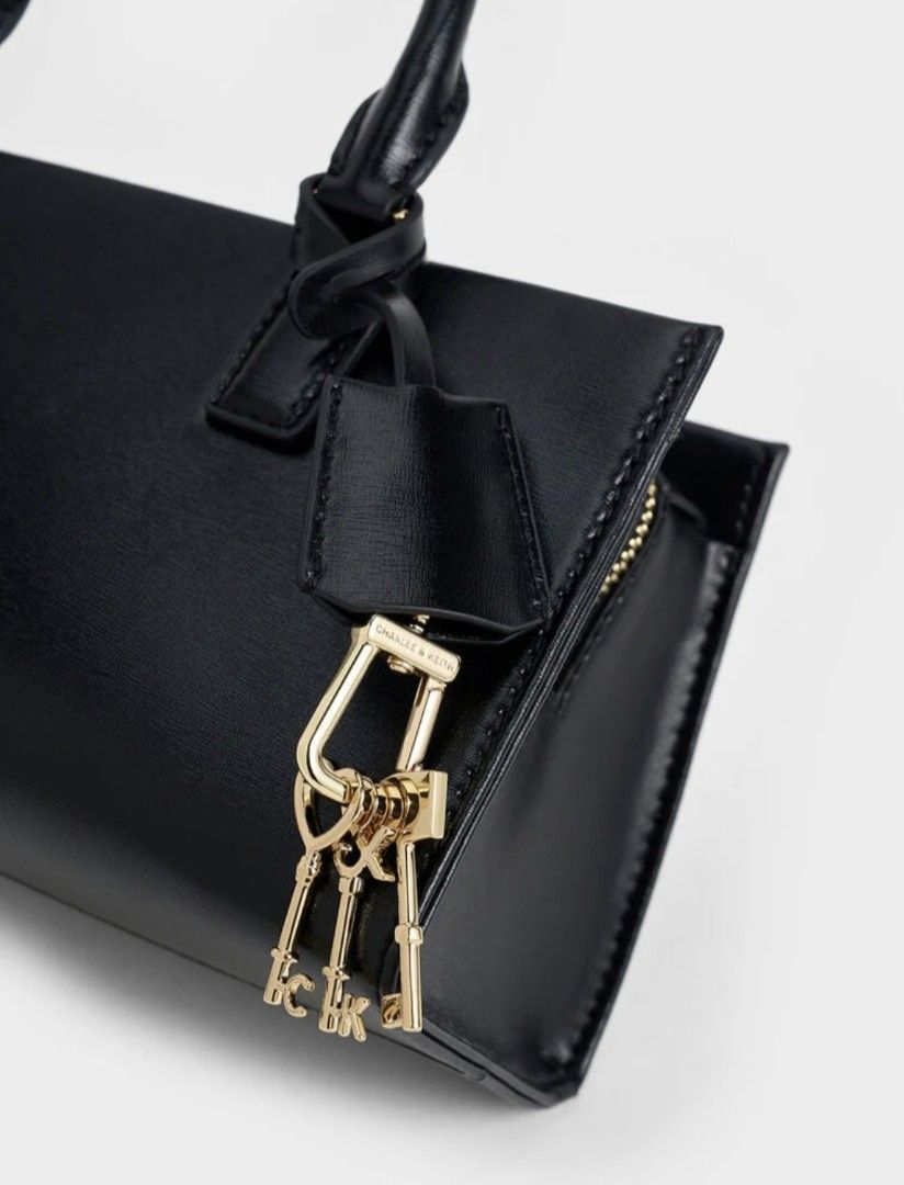 Black Top Handle Bag with gold Key Charm (Category: Cross-body Bags) located in Cavite. Submitted by house_of_tabitha (Listing ID 1456625678, Image 2). Description: - Classic black top handle bag by Charles & Keith - Structured rectangular design - Secure zip closure - Elegant gold hardware - Adorable key charm detail - Spacious interior with internal zip pocket - Versatile for daily use or evening events - Effortlessly complements any outfit.