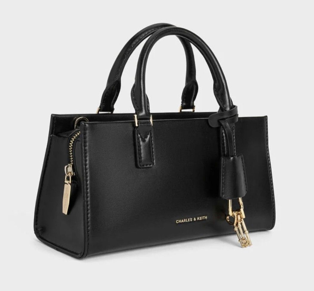Black Top Handle Bag with gold Key Charm (Category: Cross-body Bags) located in Cavite. Submitted by house_of_tabitha (Listing ID 1456625678, Image 3). Description: - Classic black top handle bag by Charles & Keith - Structured rectangular design - Secure zip closure - Elegant gold hardware - Adorable key charm detail - Spacious interior with internal zip pocket - Versatile for daily use or evening events - Effortlessly complements any outfit.