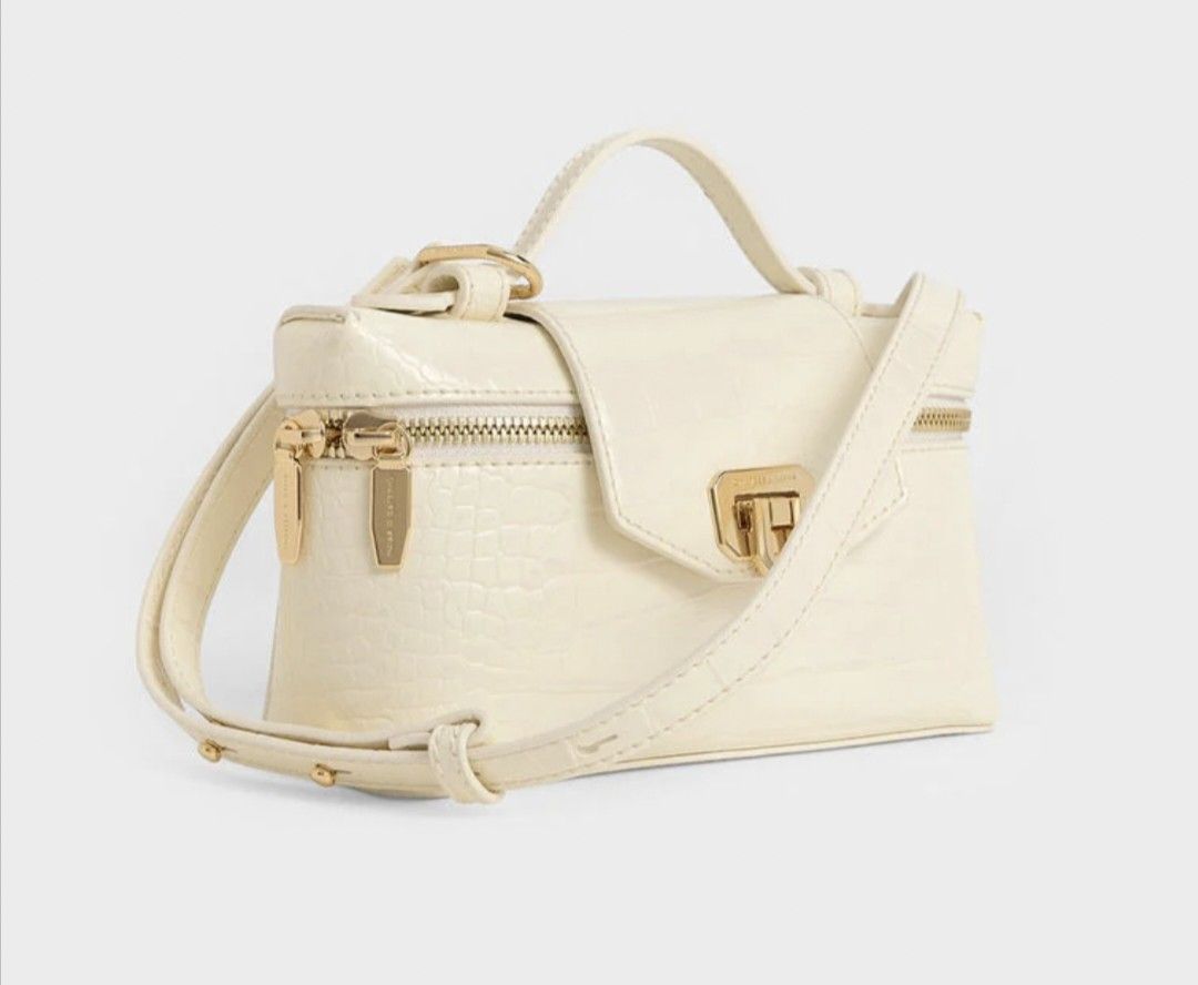 Charles & Keith White Croc Vanity Bag with Gold Hardware (Category: Cross-body Bags) located in Cavite. Submitted by house_of_tabitha (Listing ID 1456626085, Image 3). Description: - White croc-embossed vanity bag - Brand: Charles & Keith - Gold hardware - Secure clasp closure - Top handle - Detachable shoulder strap - Ideal for makeup or small essentials - Clean and chic design.
