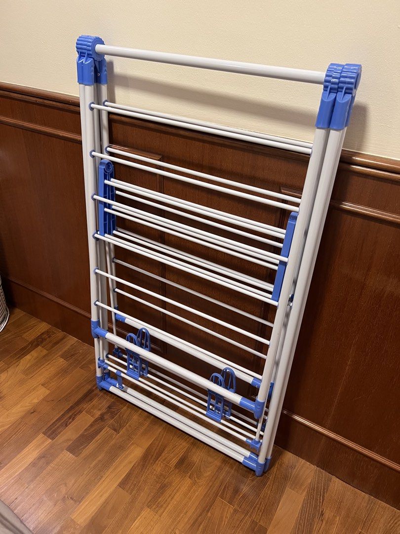 Foldable Drying Rack (Category: Clothes Drying Rack) located in Singapore. Submitted by hecarimshadowislessg (Listing ID 1456732308, Image 2). Description: ✅Price Negotiable ✅Pick up at Tiong Bahru - Foldable drying rack - Multiple hanging bars - White frame with blue plastic accents - Folds flat for easy storage - Sturdy construction - Ideal for laundry or airing items.