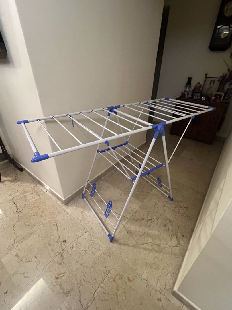 Foldable Drying Rack (Category: Clothes Drying Rack) located in Singapore. Submitted by hecarimshadowislessg (Listing ID 1456732308, Image 3). Description: ✅Price Negotiable ✅Pick up at Tiong Bahru - Foldable drying rack - Multiple hanging bars - White frame with blue plastic accents - Folds flat for easy storage - Sturdy construction - Ideal for laundry or airing items.