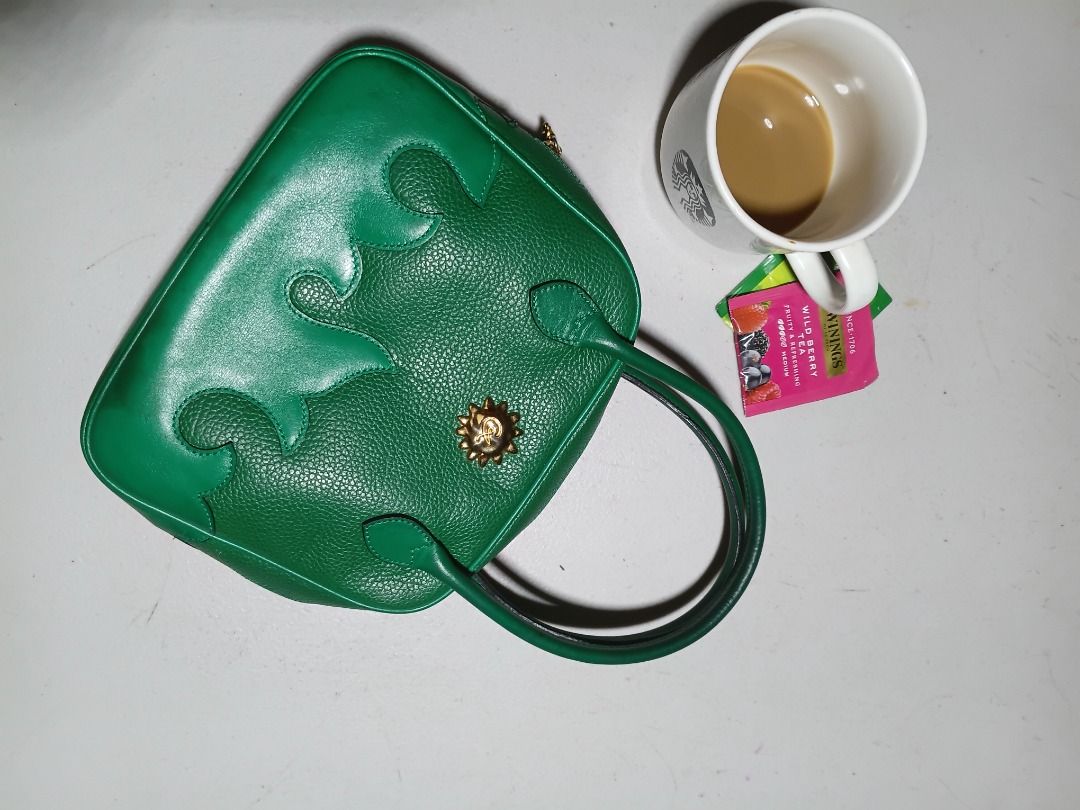 Green Puzzle Piece Handbag with Gold Accent (Category: Luxury Bags & Wallets) located in Caloocan City. Submitted by harrypotter0215 (Listing ID 1456672947, Image 1). Description: - Unique green handbag - Features a puzzle piece design - Small gold sun-like embellishment on the front - Two short handles - Adds a pop of color to any outfit - Ideal for carrying essentials.