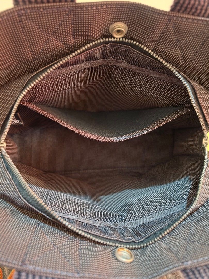 Hermes Herline PM Tote Bag (Category: Luxury Bags & Wallets) located in Cavite. Submitted by kazi_preloved (Listing ID 1456607391, Image 3). Description: - 100% Authentic Hermes Herline tote bag in PM size - Color: Dark grey canvas with signature H pattern - Closure: Zipper with interior pockets - Hardware: Silver detail on front snap - Condition: Clean inside and out.
