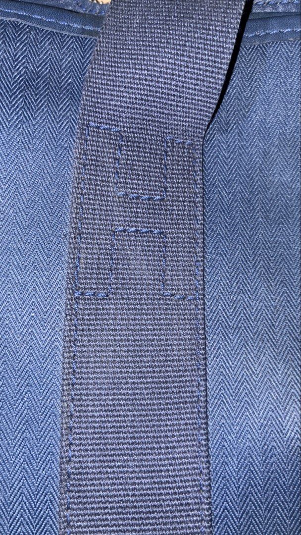 Hermes Navy Blue Nylon Tote Bag (Category: Luxury Bags & Wallets) located in Placer. Submitted by talaalond61563 (Listing ID 1456624706, Image 3). Description: - Navy blue tote bag - Durable nylon material - Iconic Hermes H detail on the front - Two comfortable top handles - Secure snap closure with Hermes Paris engraving - Ideal for everyday use.