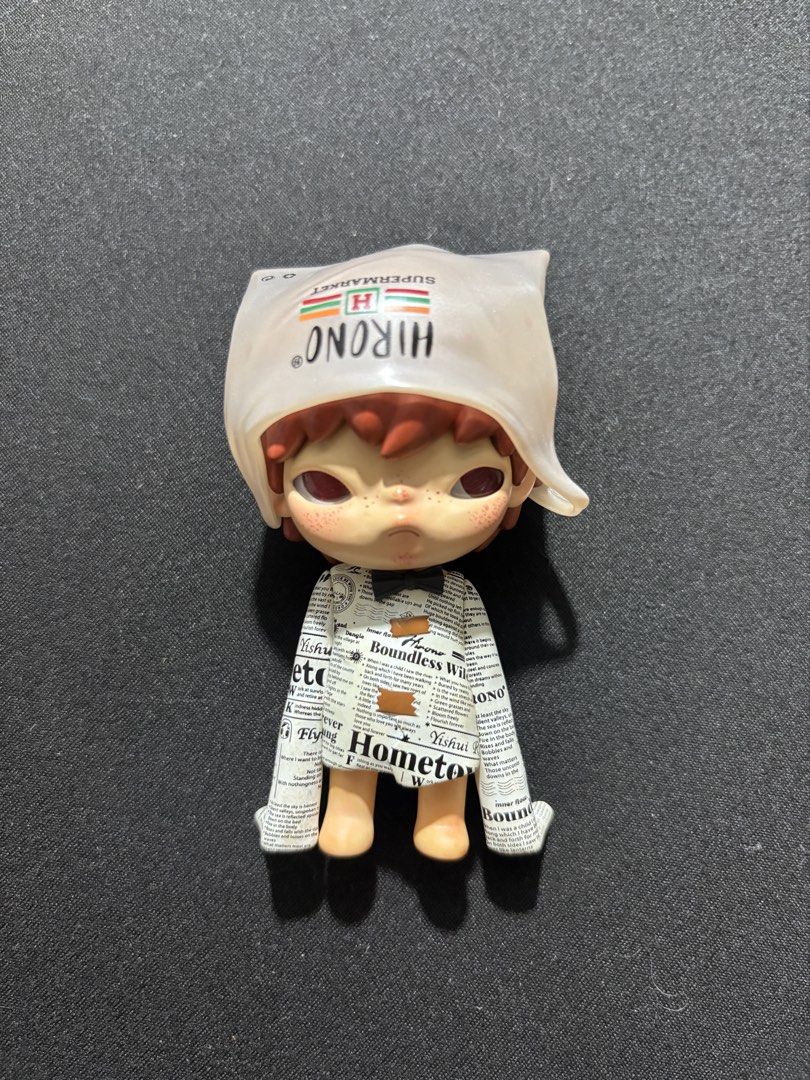 Hirono Little Mischief Series – "Ragpicker" (Category: Designer & Blind Box Toys) located in Cainta. Submitted by aquinoclar (Listing ID 1456689672, Image 1). Description: Authentic Hirono “Ragpicker” figure from the Little Mischief series. Like-new, display-only condition with no visible wear. Features Hirono wearing a translucent plastic bag hood over his head and an oversized newspaper-print outfit tied with a bow. Complete with the original b