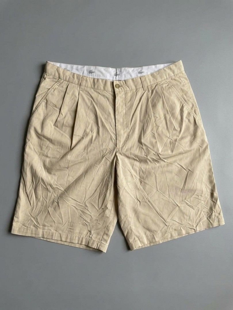 Lacoste Beige Pleated Chino Shorts (Category: Shorts) located in Manila. Submitted by gentlefalcon.29dc69 (Listing ID 1456752714, Image 1). Description: - Beige Lacoste shorts - Classic pleated style - Iconic crocodile logo on waistband - Small brown tag on back pocket - Versatile for casual or smart-casual looks - Comfortable fit.