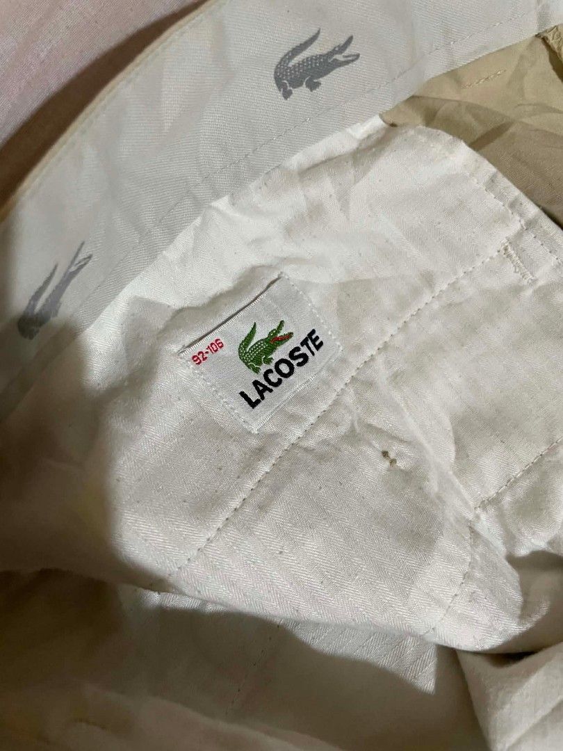 Lacoste Beige Pleated Chino Shorts (Category: Shorts) located in Manila. Submitted by gentlefalcon.29dc69 (Listing ID 1456752714, Image 3). Description: - Beige Lacoste shorts - Classic pleated style - Iconic crocodile logo on waistband - Small brown tag on back pocket - Versatile for casual or smart-casual looks - Comfortable fit.