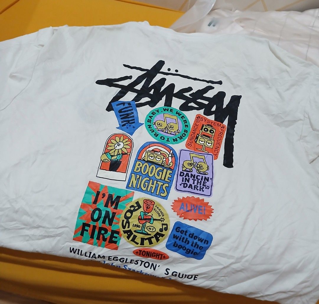 Stussy Graphic T-Shirt (Category: Tshirts & Polo Shirts ) located in Daraga. Submitted by thethriftcity2024 (Listing ID 1456740603, Image 1). Description: - White Stussy T-shirt - Unique graphic print on the back with various patches and designs - Small Stussy logo and circular patch on the front - Ideal for casual wear and streetwear style - Great for fans of the Stussy brand Excellent 21 x 28 cut tag issue 500+sf thank you.