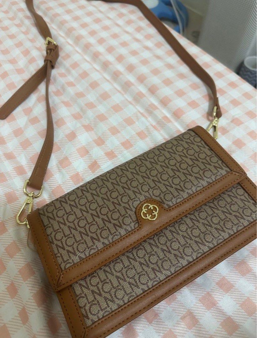 Brown Monogram Crossbody Bag with Leather Trim (Category: Cross-body Bags) located in Valenzuela. Submitted by shopwithmika (Listing ID 1456920055, Image 1). Description: - Stylish brown crossbody bag with a repeating monogram pattern. - Elegant tan leather trim and adjustable strap. - Accented with polished gold hardware. - Interior features a zippered compartment and card slots for organization. - Versatile and practical for everyday use..