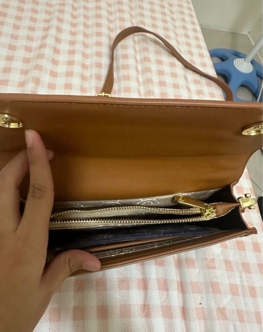 Brown Monogram Crossbody Bag with Leather Trim (Category: Cross-body Bags) located in Valenzuela. Submitted by shopwithmika (Listing ID 1456920055, Image 2). Description: - Stylish brown crossbody bag with a repeating monogram pattern. - Elegant tan leather trim and adjustable strap. - Accented with polished gold hardware. - Interior features a zippered compartment and card slots for organization. - Versatile and practical for everyday use..