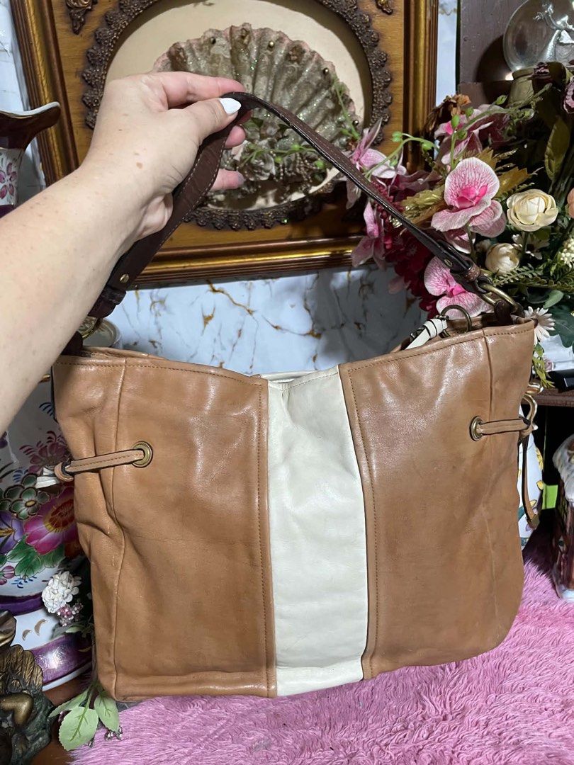 Coach Brown Leather Hobo Bag with White Stripe (Category: Luxury Bags & Wallets) located in Manila. Submitted by popofcolor.ph (Listing ID 1456793919, Image 3). Description: - Authentic Coach brown leather hobo bag - Features a stylish white stripe down the front - Unique drawstring details on the sides - Durable leather strap with polished metal hardware - Comes with the original Coach hangtag - Ideal for everyday wear and versatile styling.