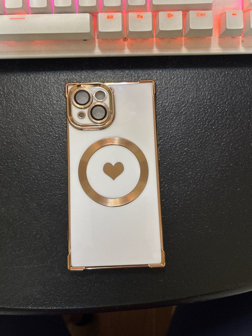 iPhone 15 case (Category: Cases & Sleeves) located in Malabon City. Submitted by luxgoals (Listing ID 1456785657, Image 1). Description: - Designed for iPhone 15 - Stylish white finish with rose gold accents - Features a cute heart design on the back - MagSafe compatible for easy charging and accessory attachment - Sleek and protective - Condition: 4/5 stars.
