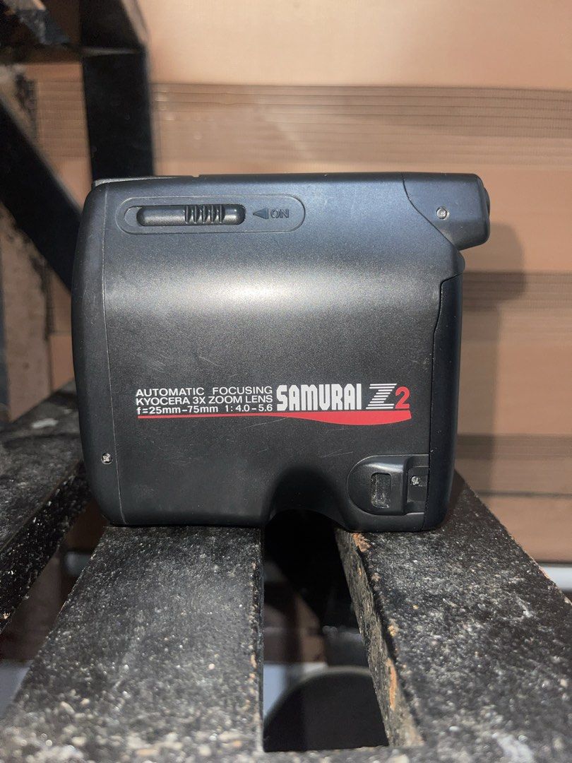 Kyocera Samurai Z2 Automatic Focusing Zoom Lens Camera (Category: Cameras) located in Manila. Submitted by polavoid (Listing ID 1456881054, Image 2). Description: Kyocera Samurai Z2 camera. Automatic focusing zoom lens. A half frame camera that has a Lens is f=25mm-75mm 1:4.0-5.6. And a grip strap. Great for capturing memories. Fully working, zoom and flash, tested with spare batteries (NOT INCLUDED) but no film to test it with, but everything wo