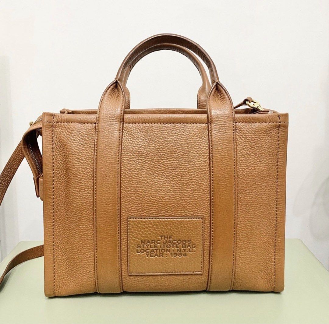 Marc Jacobs The Tote Bag (Category: Luxury Bags & Wallets) located in Makati City. Submitted by aideclutter (Listing ID 1456919228, Image 3). Description: • Used only a few times • Bought in Greenbelt • Ideal as an office/work bag • Size : 12.5in (W) x 10in (H) x 6in (D) • Color: Argan Oil • Material: Full-grain leather • Top zip closure • Interior pockets • Adjustable and removable crossbody strap • With dustbag • No box • No more paperbag • Ser
