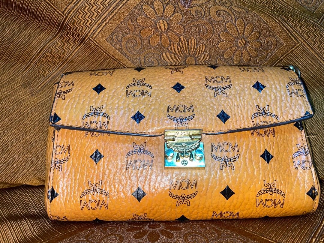 MCM Monogram Clutch Bag (Category: Luxury Bags & Wallets) located in Rosales. Submitted by jmghalib7755166 (Listing ID 1456834770, Image 2). Description: - Authentic MCM clutch - Classic MCM monogram print - Tan leather interior with zippered pocket - Gold-tone hardware - Clasp closure - Ideal for evenings or as a statement piece.