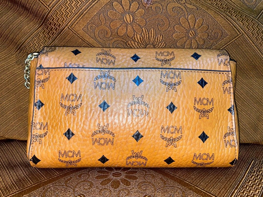 MCM Monogram Clutch Bag (Category: Luxury Bags & Wallets) located in Rosales. Submitted by jmghalib7755166 (Listing ID 1456834770, Image 3). Description: - Authentic MCM clutch - Classic MCM monogram print - Tan leather interior with zippered pocket - Gold-tone hardware - Clasp closure - Ideal for evenings or as a statement piece.