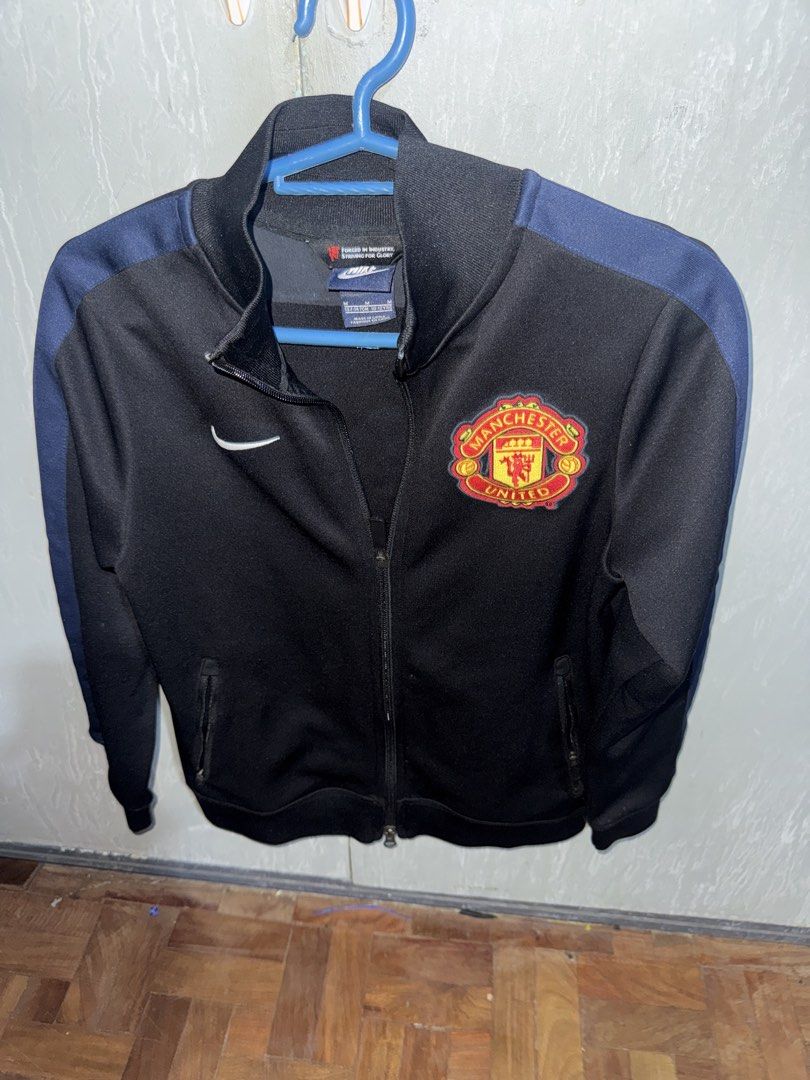 Nike Manchester United Track Jacket (Category: Fragrance & Deodorants) located in Angeles City. Submitted by migs_font29 (Listing ID 1456821028, Image 1). Description: - Official Nike Manchester United track jacket - Color: Black - Features the Manchester United crest on the chest - 'Manchester United' text printed on the back - Size: 137-147cm (suitable for 10-12 years old) - Made in China.