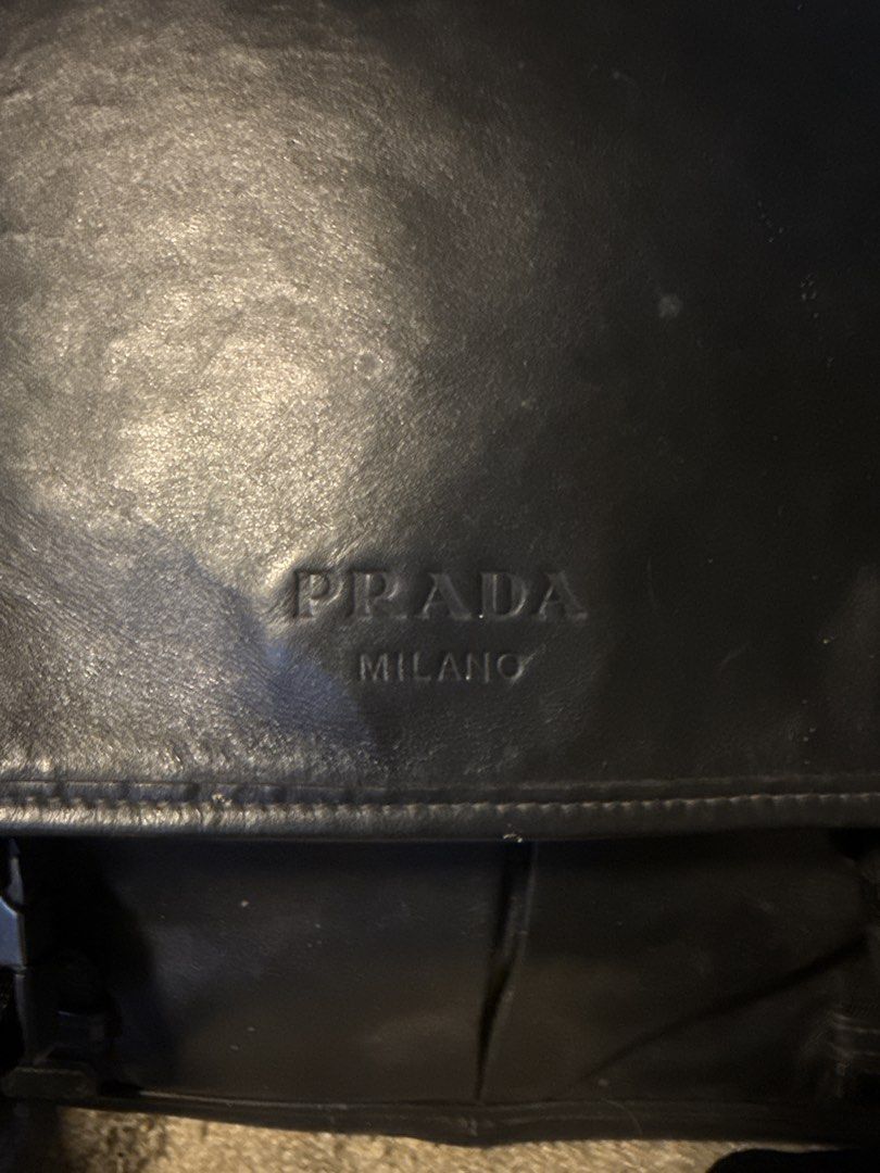 Prada Black Leather Messenger Bag (Category: Tailoring & Restoration) located in Angeles City. Submitted by migs_font29 (Listing ID 1456881587, Image 2). Description: - Authentic black leather Prada messenger bag - Prada Milano logo embossed on front flap - Prada logo printed on adjustable strap - Secure buckle closure - Shows some signs of wear on buckle and strap - Ideal for everyday use.