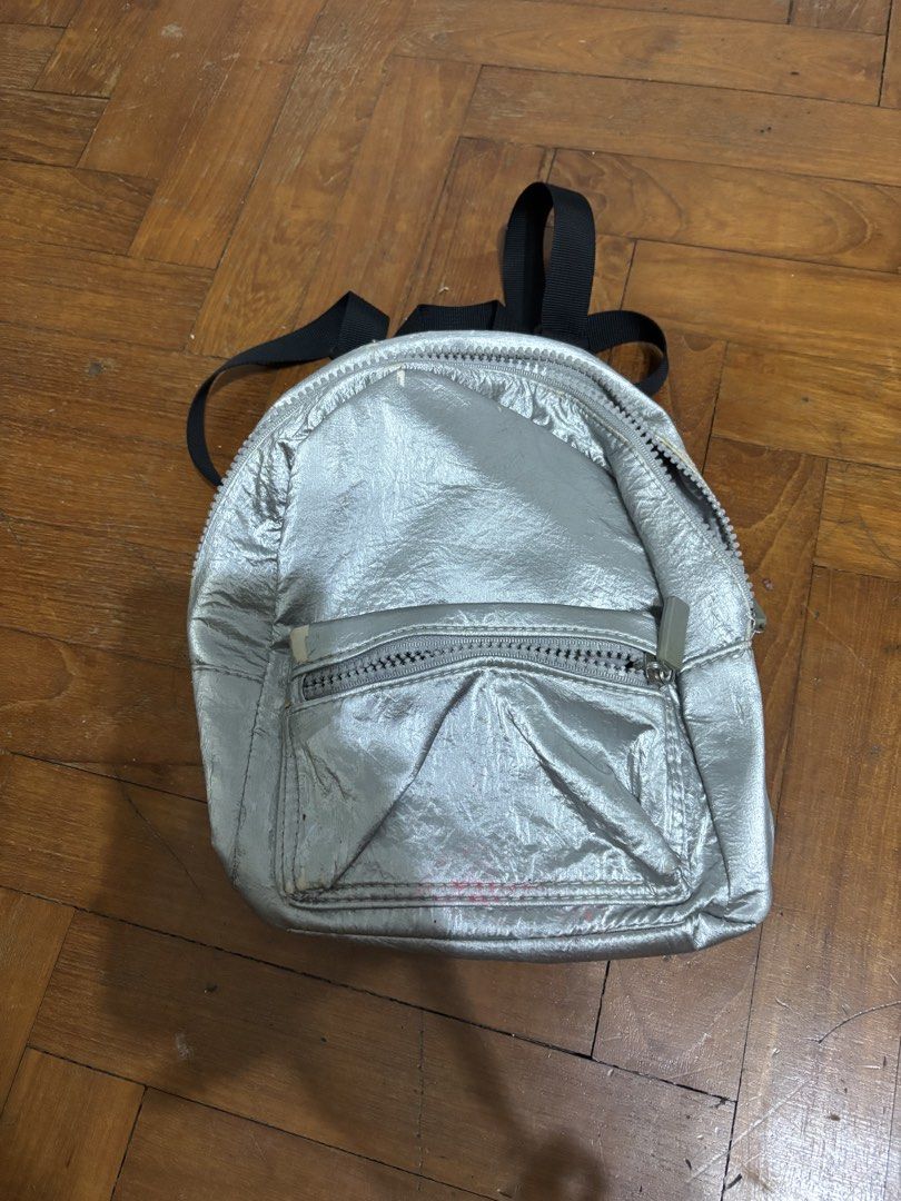 Silver Mini Backpack (Category: Backpacks) located in Singapore. Submitted by marie.cbs (Listing ID 1456933945, Image 1). Description: - Cute silver mini backpack - Front zip pocket and main compartment - Adjustable straps - Ideal for essentials - Minor signs of wear on front zipper area.