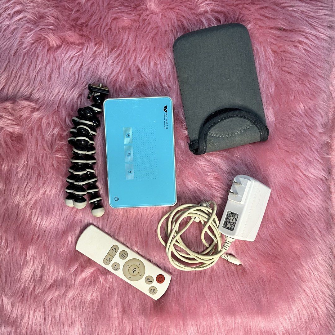 WOWOTO Mini Projector with Remote, Tripod, and Accessories (Category: Projectors) located in Caloocan City. Submitted by lovedbychin_ (Listing ID 1456911422, Image 2). Description: - WOWOTO Mini Projector: Compact and portable for entertainment on the go. - Includes: Remote control, flexible tripod, power adapter, and protective sleeve. - Connectivity: HDMI/MHL, USB ports, and micro SD card slot. - Ideal for: Movie nights, presentations, and more
