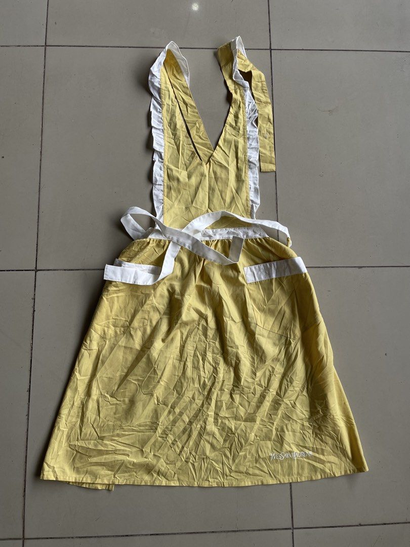 Yves Saint Laurent Yellow Ruffled Apron (Category: Luxury Apparel) located in Lucena. Submitted by riyizthriftz (Listing ID 1456905606, Image 2). Description: - Bright yellow apron with charming white ruffles and trim. - Features two convenient front pockets. - Adjustable ties for a comfortable, custom fit. - Discreetly embroidered YSL logo on the hem. - Perfect for culinary adventures or as a stylish costume element. - Approximate measurements: 