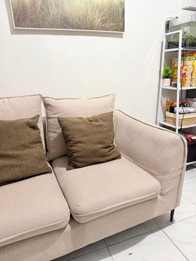 2-Seater Beige Sofa with Throw Pillows (Category: Sofas) located in Manila. Submitted by ellebarbacion (Listing ID 1457108812, Image 2). Description: - Comfortable 2-seater sofa - Neutral beige fabric - Comes with two dark brown throw pillows - Clean lines with modern black legs - Fits well in most living spaces - Ideal for apartments or smaller rooms - Ready for a new home.