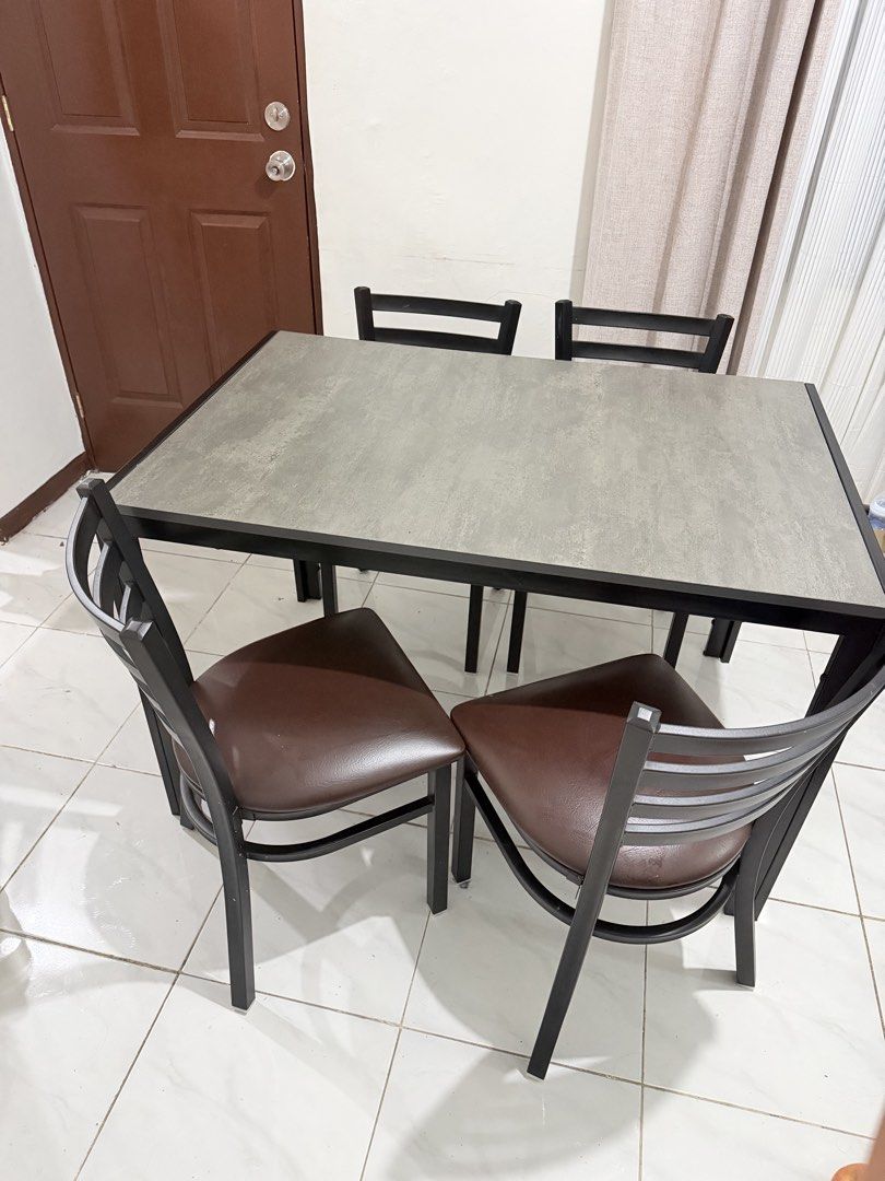 4-Seater Dining Table and Chairs Set (Category: Tables & Sets) located in Manila. Submitted by ellebarbacion (Listing ID 1457130200, Image 2). Description: - Compact dining set designed for small spaces - Table features a grey textured top and black metal frame - Includes four chairs with black metal frames - Chairs have comfortable brown faux leather seats - Perfect for kitchens or dining nooks - Easy to clean and maintain.