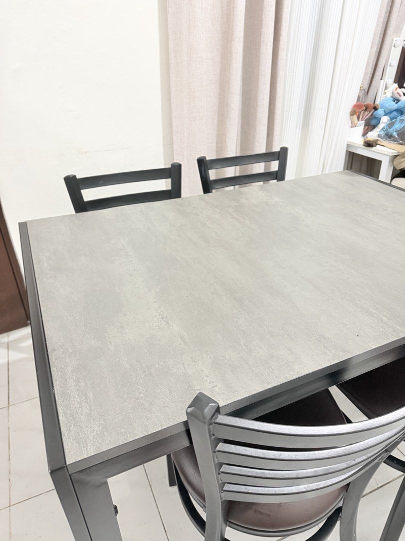4-Seater Dining Table and Chairs Set (Category: Tables & Sets) located in Manila. Submitted by ellebarbacion (Listing ID 1457130200, Image 3). Description: - Compact dining set designed for small spaces - Table features a grey textured top and black metal frame - Includes four chairs with black metal frames - Chairs have comfortable brown faux leather seats - Perfect for kitchens or dining nooks - Easy to clean and maintain.