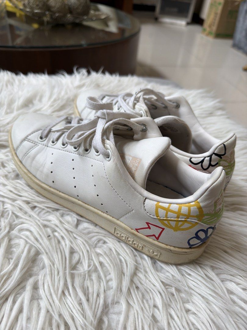 Adidas Stan Smith White Sneakers with Colorful Graphics (Category: Sneakers) located in Quezon City. Submitted by jdecino (Listing ID 1456977926, Image 2). Description: - Classic white Adidas Stan Smith sneakers - Iconic three stripes - Unique colorful graphic design on the heel - White laces - Creamy white soles - Perfect for casual wear - Shows some signs of wear Size: 8 .
