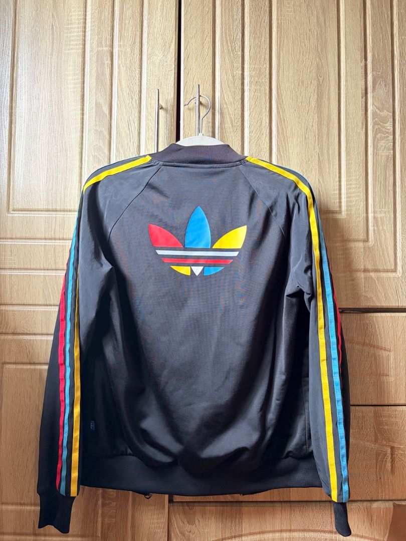 Adidas Track Jacket Rainbow Stripes (Category: Coats, Jackets and Outerwear) located in Tanza. Submitted by kmoarse (Listing ID 1457081947, Image 2). Description: - Classic Adidas track jacket - Color: Black - Iconic three stripes on sleeves (red, blue, yellow) - Rainbow Adidas logo on chest and back - Zip-up front - Features pockets - Ideal for casual wear or sports.