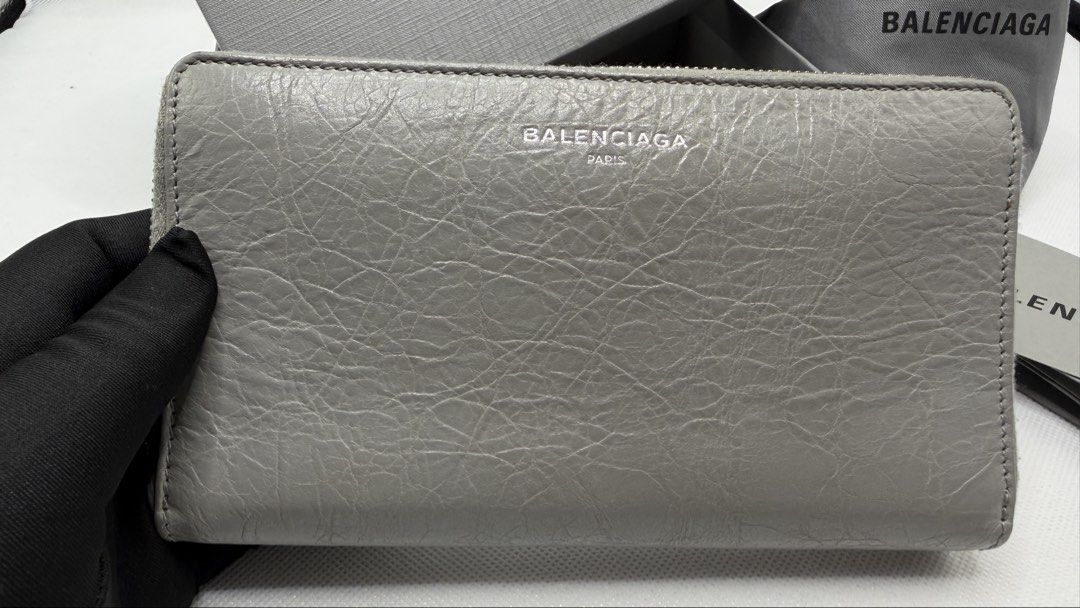 Balenciaga Grey Leather Zip Around Wallet (Category: Luxury Bags & Wallets) located in Pasig City. Submitted by shoptilyoudrop87 (Listing ID 1457133232, Image 2). Description: - Authentic Balenciaga zip around wallet - Color: Grey leather - Features classic Balenciaga logo on the front - Includes original box, dust bag, and authenticity card -Barely noticeable transfer stain as seen in the photo - Ample space for cards and cash - Ideal for everyd