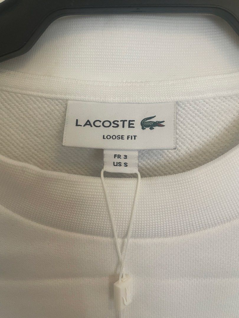 Lacoste pullover/ sweatshirt (Category: Coats, Jackets and Outerwear) located in Manila. Submitted by alldayshoppinggirl (Listing ID 1457012802, Image 3). Description: 💯 ORIGINAL BRANDNEW WITH TAG STORE BOUGHT NEGOTIABLE White Lacoste loose-fit fleece crewneck sweatshirt featuring a large collegiate-style blue block logo layered over a green crocodile graphic on the chest. Neckline is Classic ribbed crewneck collar with a visible brand tag while
