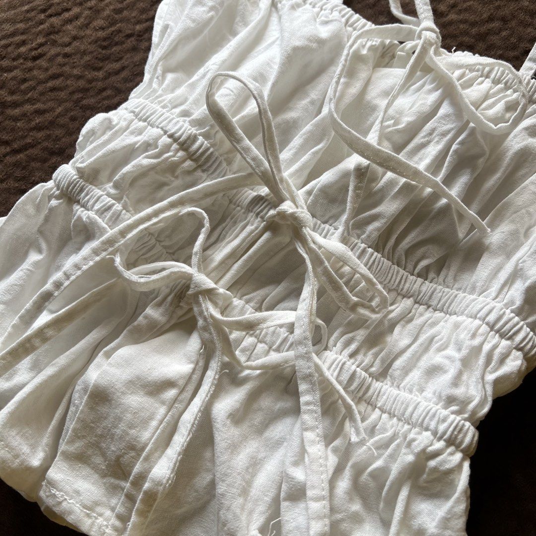 Linen ruched ribbon tie fitted top (Category: Sleeveless) located in Makati City. Submitted by monu__ (Listing ID 1456973201, Image 2). Description: Linen top Off white color, soft girl aesthetic Self tie / ribbon top Ruched, fitted, very stretchy, body hugging Adjustable U wont see skin underneath when tied which i loveee coz theres an inch of fabric from where the ties start (check last image) Size: small Shushi dupe! But butter imo.