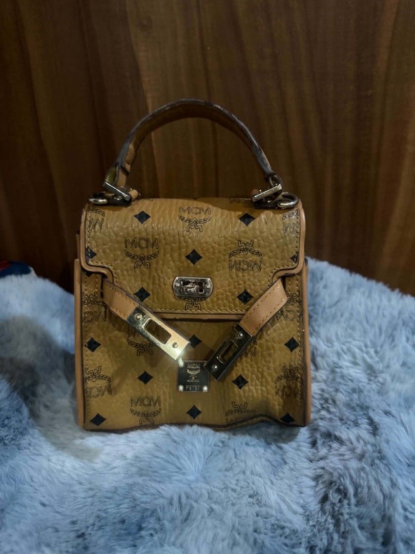MCM Monogram Mini Top Handle Bag (Category: Luxury Bags & Wallets) located in Bacolod City. Submitted by asheroth77 (Listing ID 1457071569, Image 2). Description: - Cute MCM mini bag - Classic all-over monogram print - Tan leather trim and handle - Gold hardware with twist lock closure - Lined interior - Small and compact, ideal for essentials - Handle shows some wear - Lock mechanism is functional.