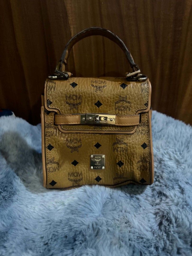 MCM Monogram Mini Top Handle Bag (Category: Luxury Bags & Wallets) located in Bacolod City. Submitted by asheroth77 (Listing ID 1457071569, Image 1). Description: - Cute MCM mini bag - Classic all-over monogram print - Tan leather trim and handle - Gold hardware with twist lock closure - Lined interior - Small and compact, ideal for essentials - Handle shows some wear - Lock mechanism is functional.