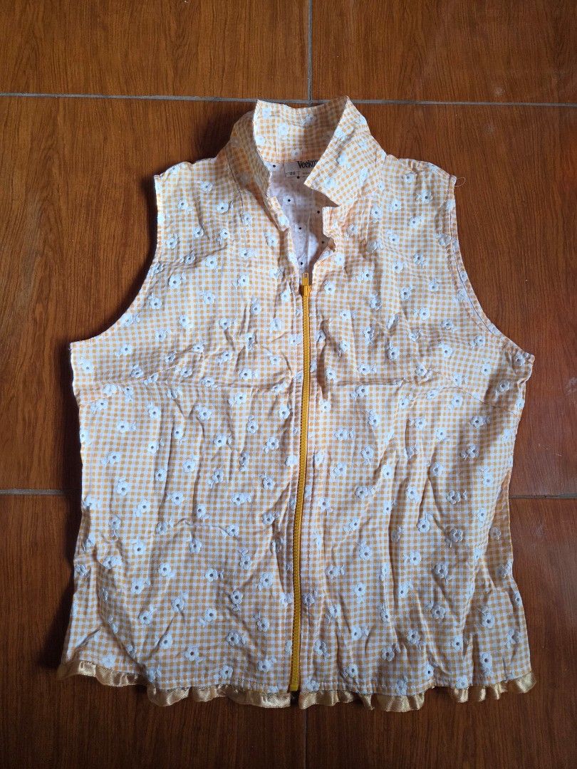 Orange Summer Eyelet Y2K Top (Category: Sleeveless) located in Manila. Submitted by declutterwtly (Listing ID 1425388088, Image 2). Description: Send me your offers, TYSM! ♡ -Sleeveless top features a charming yellow gingham pattern with white floral eyelet accents. -It has a collared neckline and a full-length zipper. -It has a ruffled hem detail..