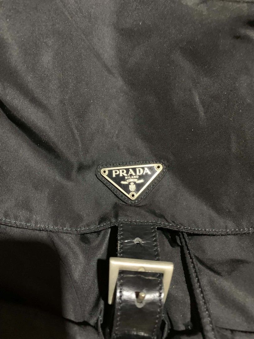 Prada Nylon Backpack Black (Category: Luxury Bags & Wallets) located in Gapan. Submitted by cleverstar.36492b (Listing ID 1457058643, Image 3). Description: Authentic Prada backpack. Black nylon material. Has front pockets with buckle closures. Drawstring and buckle flap closure. Silver hardware. Interior has a zipper pocket. Some signs of wear on the leather straps and buckles. Still a great bag..