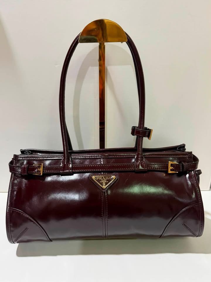 Preloved Prada Bonnie Medium Bag (Category: Luxury Bags & Wallets) located in Manila. Submitted by bagsandmanymanymore1 (Listing ID 1457034689, Image 1). Description: - Preloved Prada -size 32cm Medium - Material: Burgundy Patent Leather - Hardware: Gold-tone - Features: Adjustable buckle straps on handles, classic Prada triangle logo on front - Shape: Sleek, cylindrical - Versatility: Great for everyday use or a night out.
