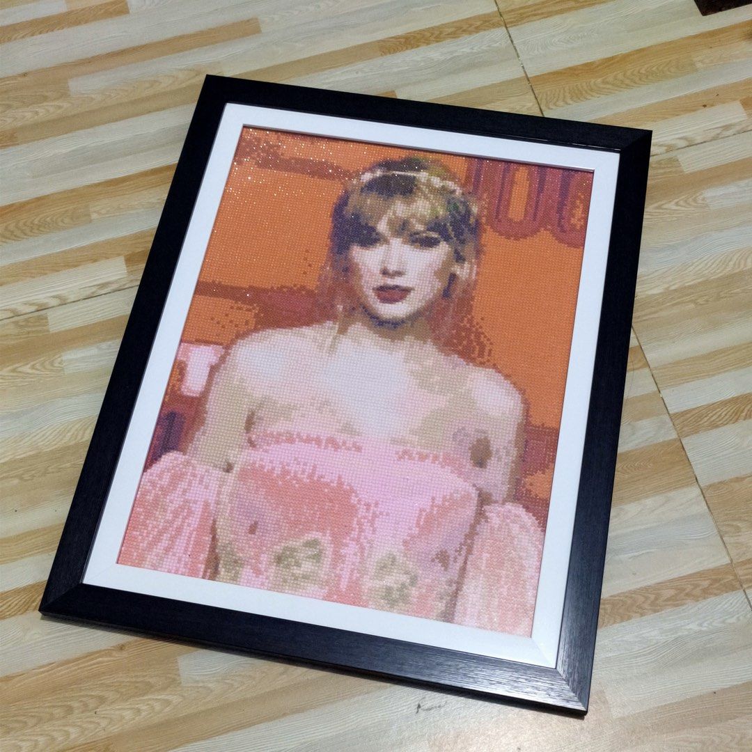 Taylor Swift Diamond Painting Framed Art (Category: Art & Prints) located in Binan City. Submitted by astrodenz (Listing ID 1456970747, Image 1). Description: - Stunning framed diamond painting of Taylor Swift. - Depicts Taylor in a vibrant pink dress against an orange backdrop. - Exquisite detail with sparkling gems that catch the light. - Comes in a sleek black frame with elegant white matting. - A must-have collectible for any dedicated Swifti