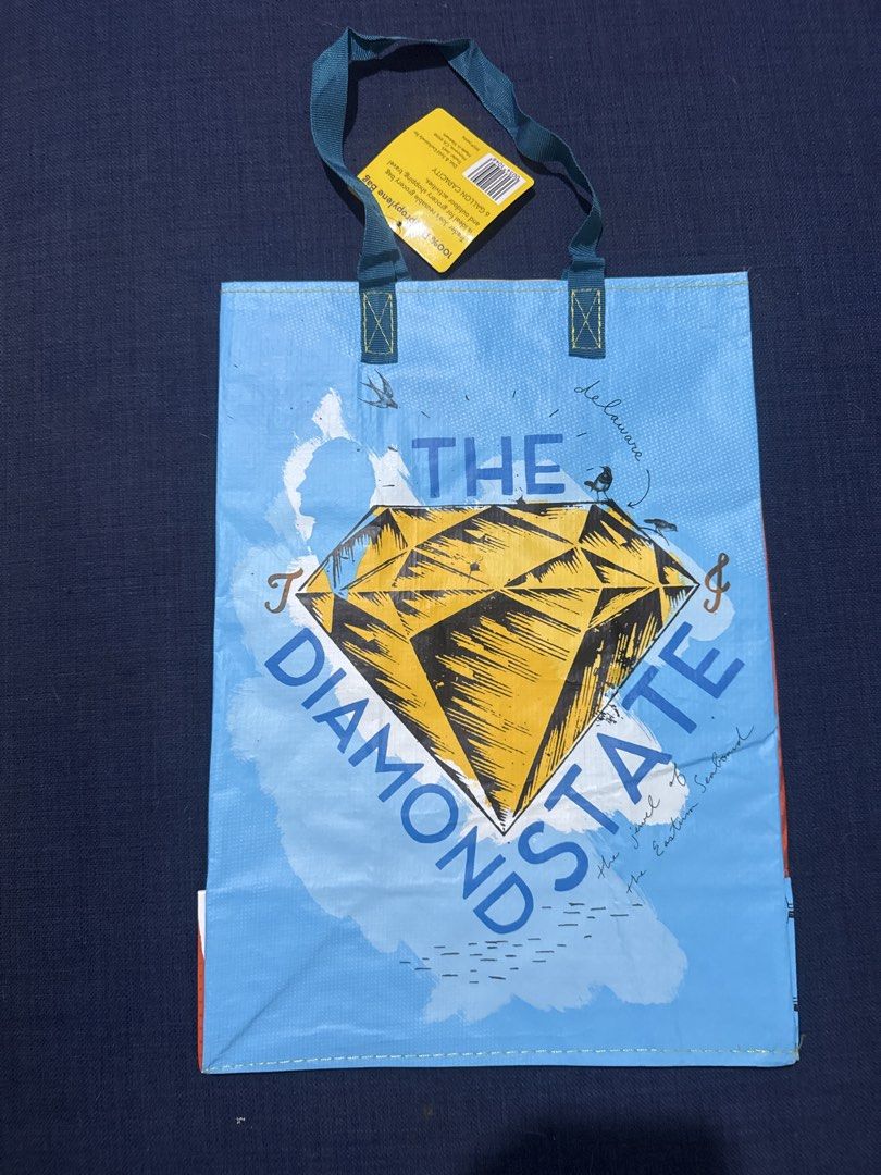 Trader Joe's Delaware "The Diamond State" Reusable Bag (Category: Tote Bags) located in Caloocan City. Submitted by ruthay23 (Listing ID 1456996750, Image 2). Description: - Authentic Trader Joe's reusable bag from Delaware. - Features "First State" with a blue hen on one side. - Features "The Diamond State" with a large diamond on the other side. - Made from 85% recycled content. - Designed for at least 125 uses. - Ideal for grocery shopping or 