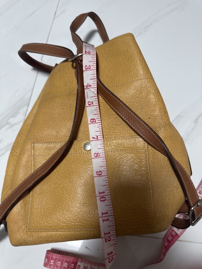 2027 WS4 Junko Shimada Yellow Leather Backpack with Brown Straps (Category: Backpacks) located in Silang. Submitted by sari2bilina (Listing ID 1457157174, Image 2). Description: - Stylish yellow leather backpack - Contrasting brown leather straps - Convenient front pocket with button closure - Adjustable straps for a comfortable fit - Dimensions: Approx. 13" H x 10" W x 5" D - Ideal for everyday use.