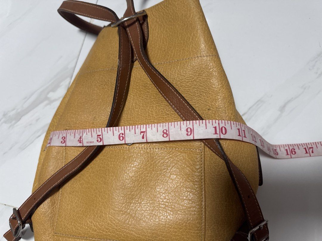 2027 WS4 Junko Shimada Yellow Leather Backpack with Brown Straps (Category: Backpacks) located in Silang. Submitted by sari2bilina (Listing ID 1457157174, Image 3). Description: - Stylish yellow leather backpack - Contrasting brown leather straps - Convenient front pocket with button closure - Adjustable straps for a comfortable fit - Dimensions: Approx. 13" H x 10" W x 5" D - Ideal for everyday use.