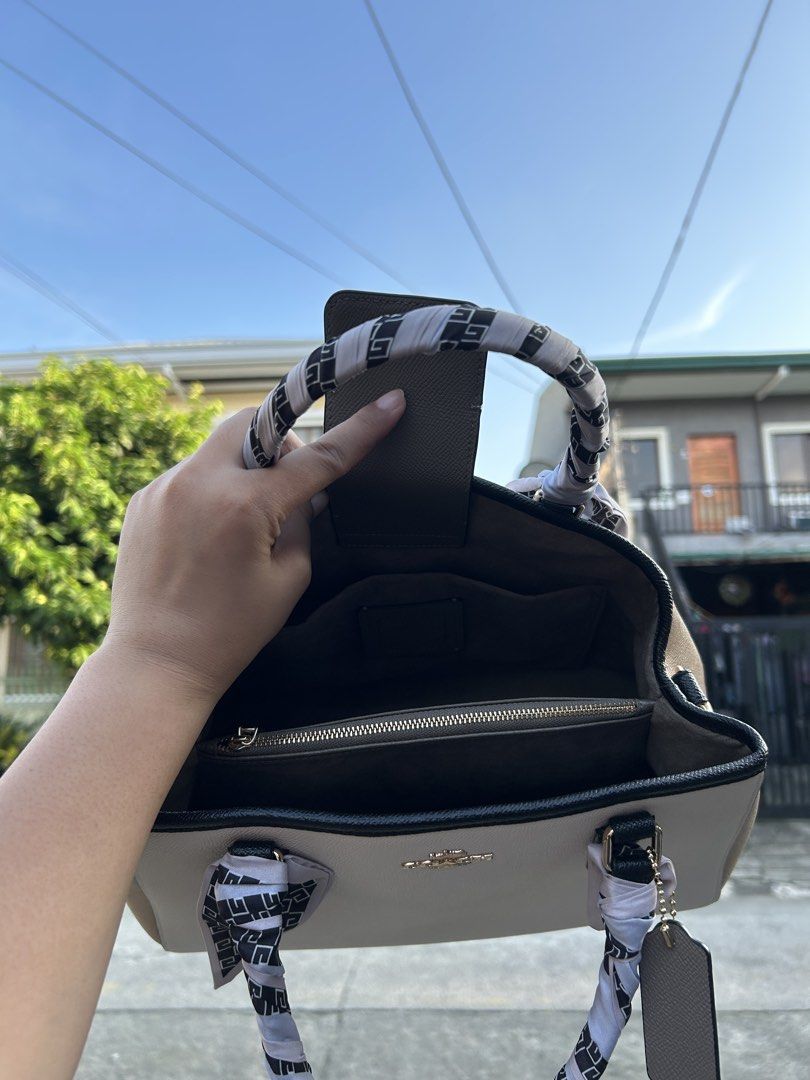 Coach Leather Handbag with Scarf Accent (Category: Luxury Bags & Wallets) located in Cainta. Submitted by claire.balbada (Listing ID 1457225160, Image 3). Description: - Classic Coach handbag in light grey and tan colorblock. - Elegant black trim and decorative scarf tied to handles. - Interior includes a zippered pocket and multiple compartments for organization. - Accented with sophisticated gold hardware. - A versatile and timeless addition to