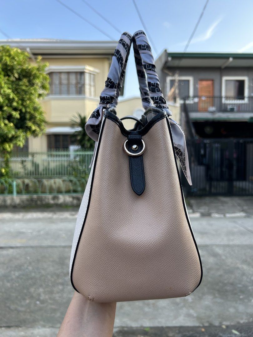 Coach Leather Handbag with Scarf Accent (Category: Luxury Bags & Wallets) located in Cainta. Submitted by claire.balbada (Listing ID 1457225160, Image 2). Description: - Classic Coach handbag in light grey and tan colorblock. - Elegant black trim and decorative scarf tied to handles. - Interior includes a zippered pocket and multiple compartments for organization. - Accented with sophisticated gold hardware. - A versatile and timeless addition to