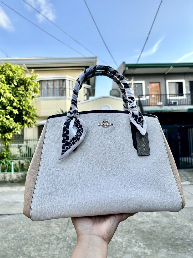 Coach Leather Handbag with Scarf Accent (Category: Luxury Bags & Wallets) located in Cainta. Submitted by claire.balbada (Listing ID 1457225160, Image 1). Description: - Classic Coach handbag in light grey and tan colorblock. - Elegant black trim and decorative scarf tied to handles. - Interior includes a zippered pocket and multiple compartments for organization. - Accented with sophisticated gold hardware. - A versatile and timeless addition to