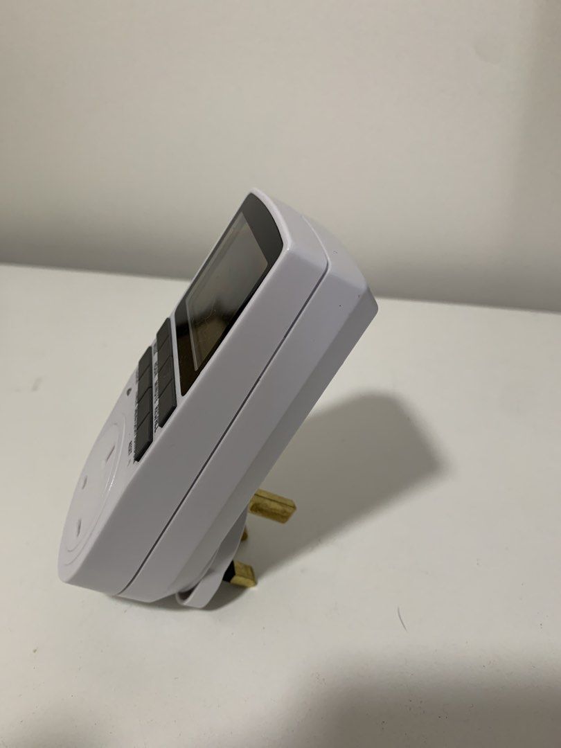 Digital Timer Plug Socket Outlet Timer UK Digital Plug Socket, Electrical Programmable Timer Switch (Category: Electrical, Adaptors & Sockets) located in Singapore. Submitted by blueberrycrisp (Listing ID 1457169761, Image 2). Description: - White digital timer plug - LCD screen displays time and settings - Buttons for week, hour, minute, and mode selection - Standard UK plug socket - Ideal for controlling various appliances.