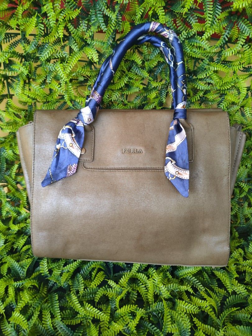 Furla Leather Handbag with Scarf Accent (Category: Luxury Bags & Wallets) located in Davao. Submitted by asherbenedict24 (Listing ID 1457194159, Image 1). Description: - Authentic Furla Bag - Genuine brown leather - Adorned with a blue silk scarf (chain & buckle print) tied to handles - Multiple interior compartments for organization - Secure zipper closure - Slight signs of wear on the zipper pull -with flaws see picture attached.
