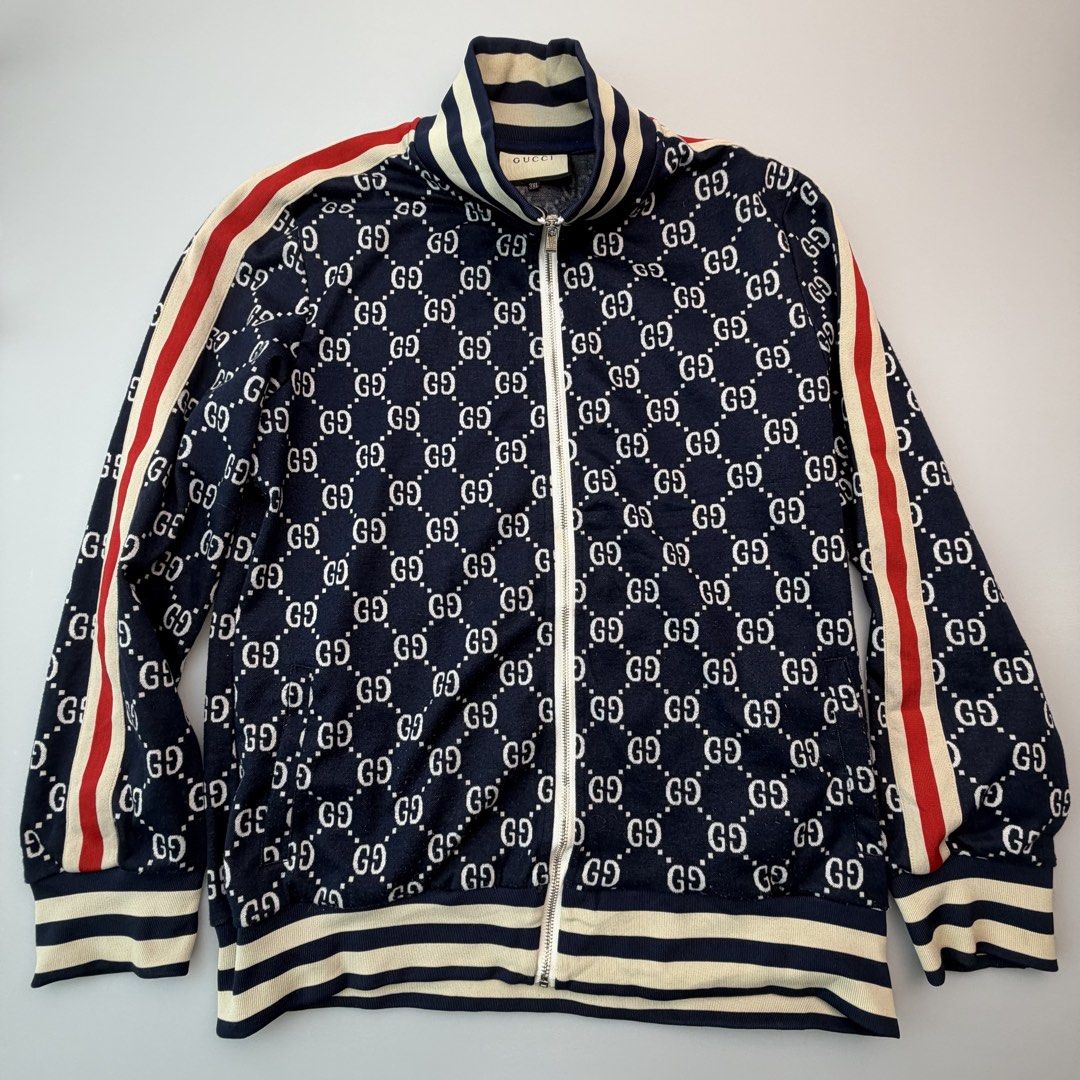 Gucci GG Monogram Web Stripe Track Jacket Navy 3XL (Category: Luxury Apparel) located in San Juan City. Submitted by vc828 (Listing ID 1457244087, Image 1). Description: Gucci full-zip track jacket featuring an all-over interlocking GG monogram design in navy and cream with the signature red and cream Web stripe running down both sleeves. Statement piece with striped rib-knit stand collar, cuffs and hem, full front zip closure, and Gucci-engraved