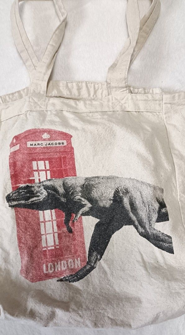Marc Jacobs London Dinosaur Tote Bag (Category: Luxury Bags & Wallets) located in Cabanatuan. Submitted by juantamadthirftshop (Listing ID 1457220772, Image 2). Description: - Eye-catching graphic tote bag - Features a red London phone booth with Marc Jacobs logo - Adorable dinosaur print on the front - Plain back for a clean look - Ideal for everyday use or as a stylish accessory - Approximate dimensions: 10 inches tall x 13 inches wide.