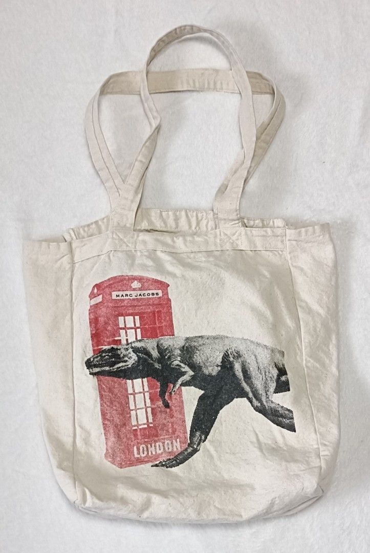 Marc Jacobs London Dinosaur Tote Bag (Category: Luxury Bags & Wallets) located in Cabanatuan. Submitted by juantamadthirftshop (Listing ID 1457220772, Image 1). Description: - Eye-catching graphic tote bag - Features a red London phone booth with Marc Jacobs logo - Adorable dinosaur print on the front - Plain back for a clean look - Ideal for everyday use or as a stylish accessory - Approximate dimensions: 10 inches tall x 13 inches wide.